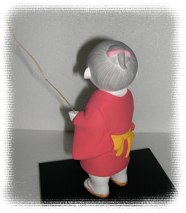 Japanese Hakata doll of a Boy in red kimono and with twig