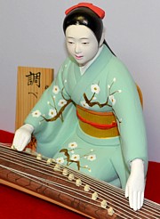 japanese clay doll of young woman playing koto